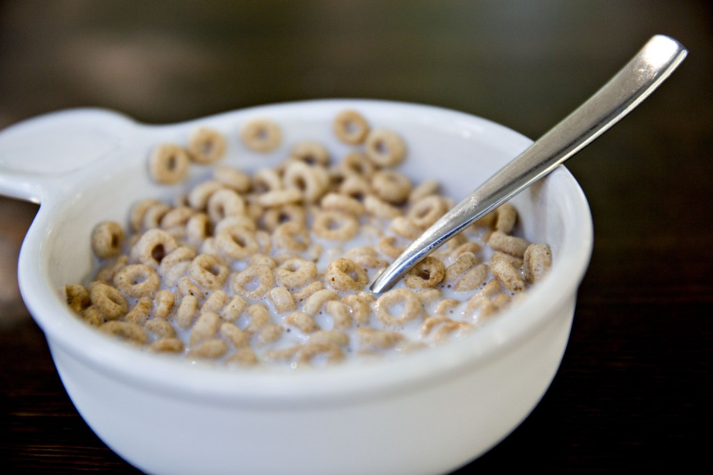 Cheerios cereal bowl with milk and a spoon.